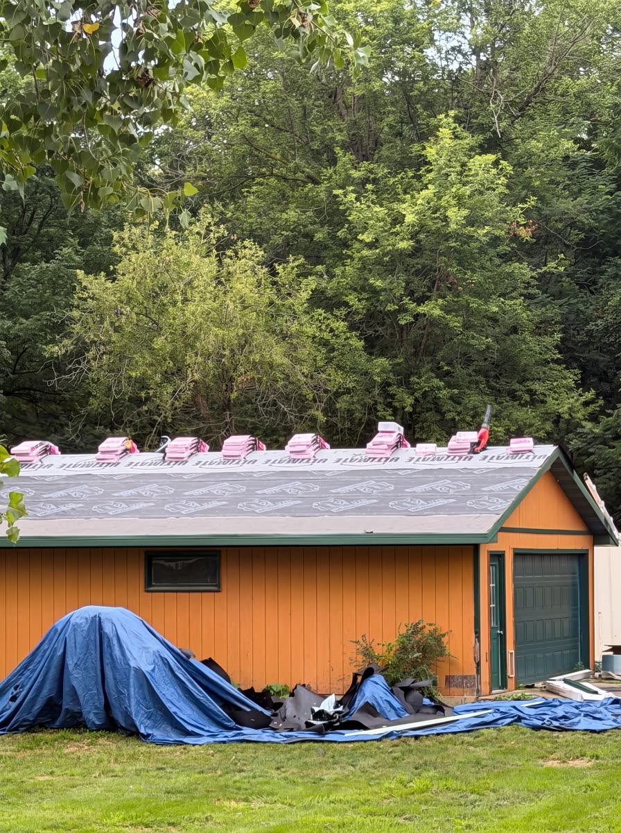 Synthetic underlayment down and shingle bundles staged along the ridge